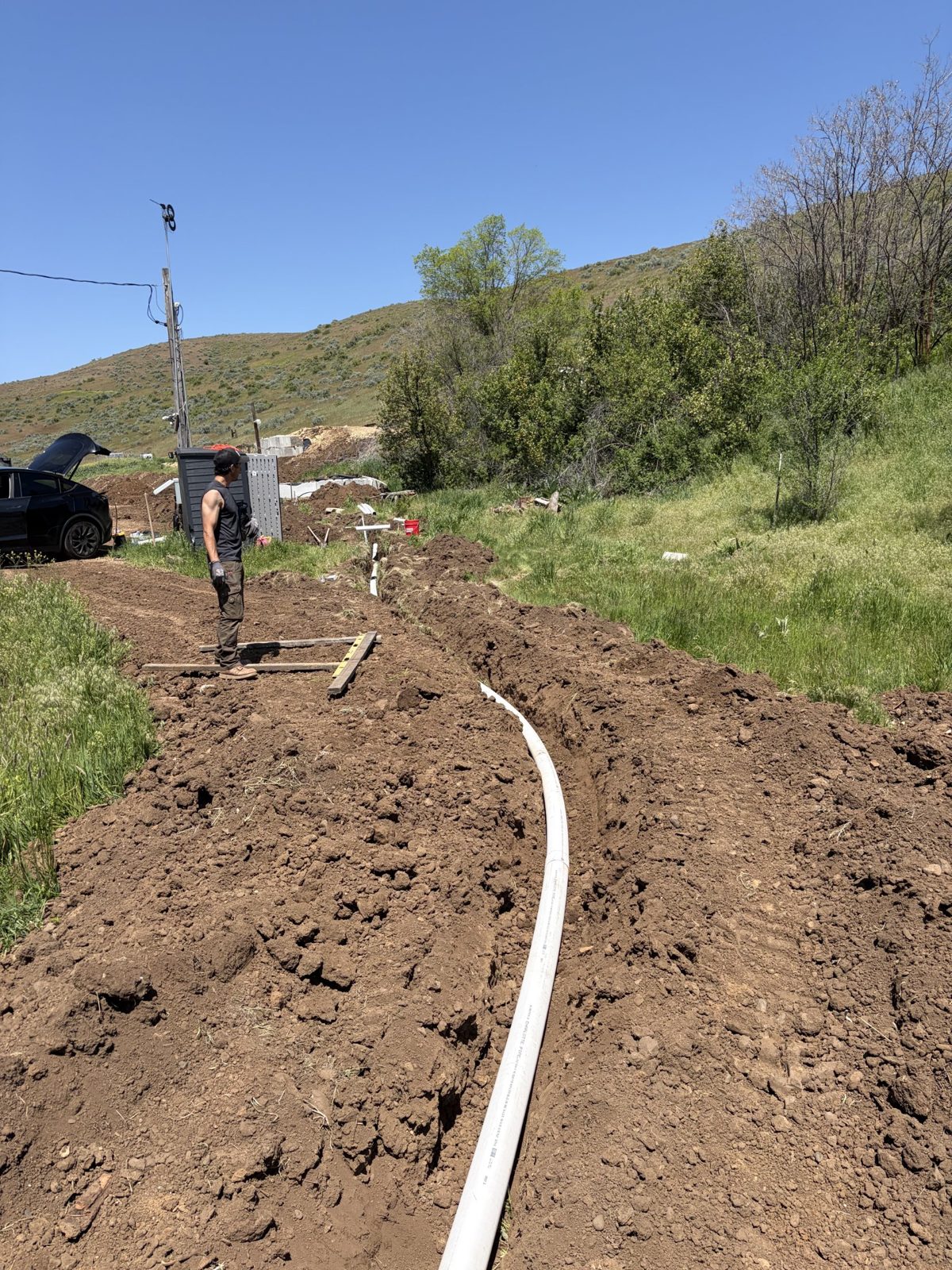 White water pipe laid along a fresh trench below the hills
