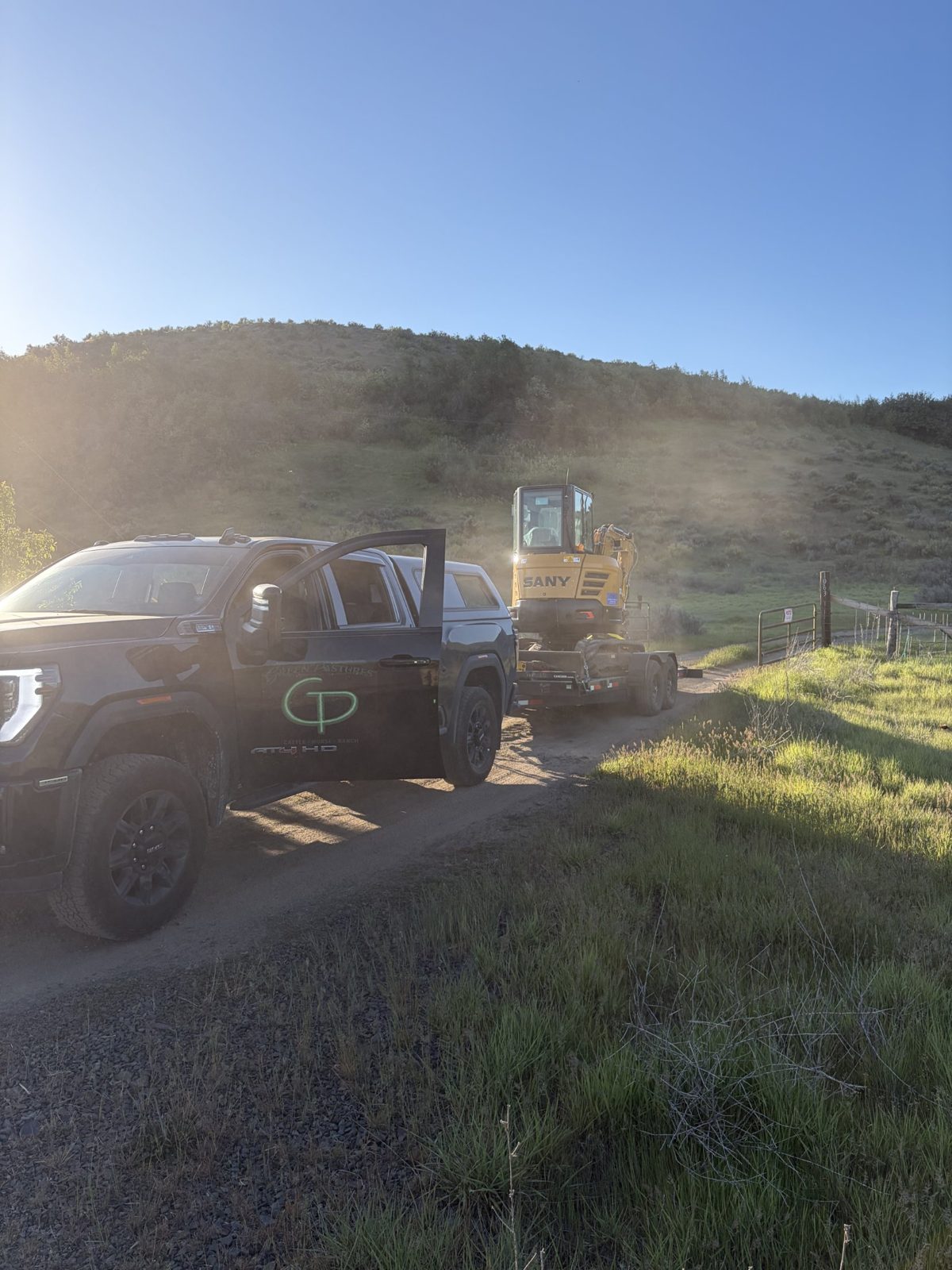 The Green Pastures truck towing an excavator to the ranch