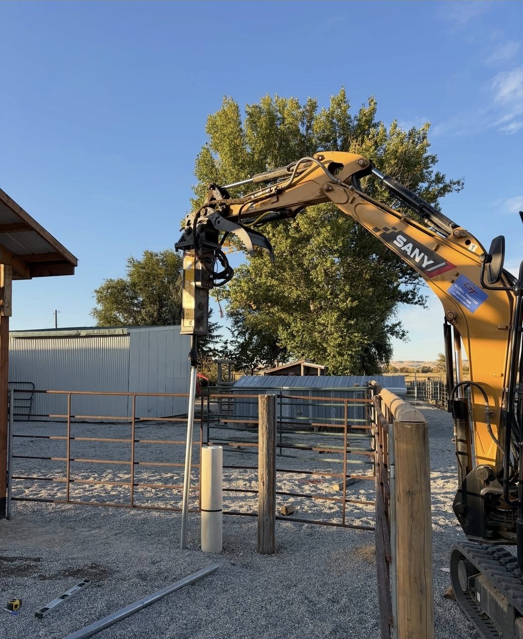An excavator setting fence posts at the ranch
