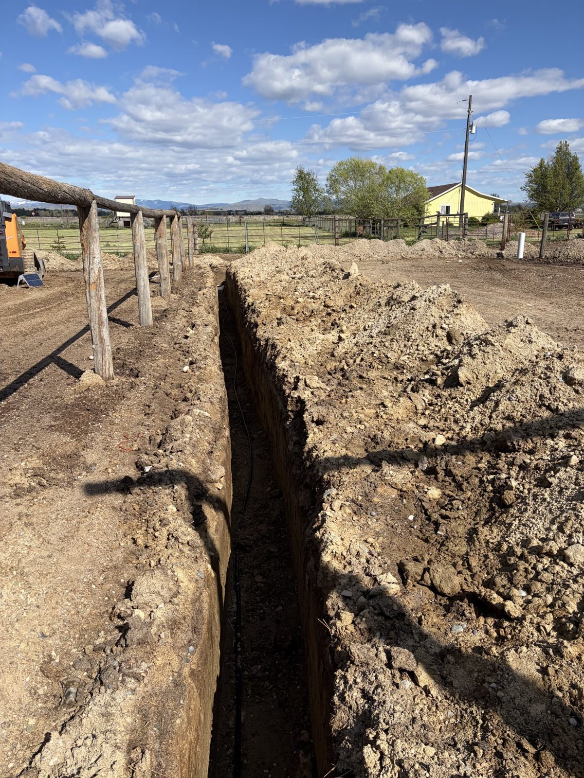 A deep water-line trench running beside the corral fence